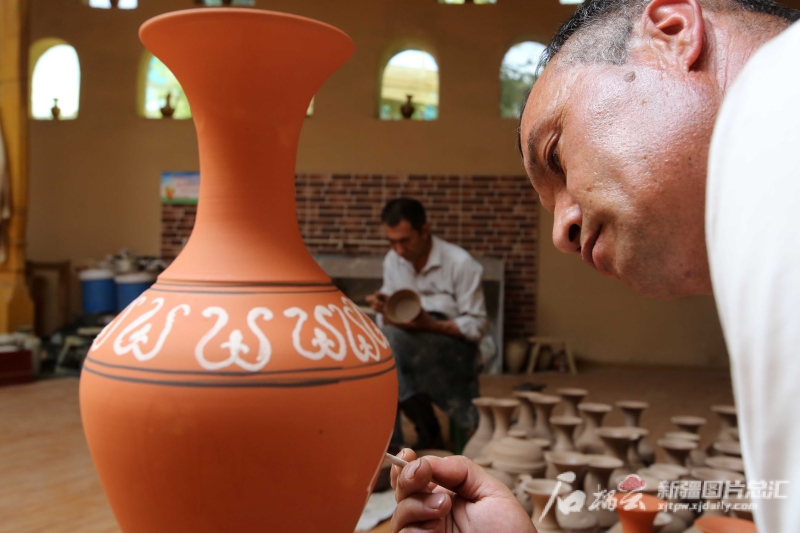 6月19日，恰克日庫(kù)依村土陶制作藝人伊馬木·艾力在土陶罐上畫(huà)畫(huà)。石榴云/新疆日?qǐng)?bào)記者 蔡增樂(lè) 攝